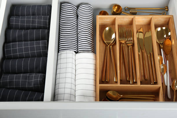 Open drawer with different utensils and folded towels. Order in kitchen