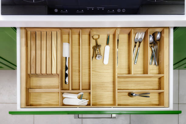 Kitchen furniture in green with open drawers.