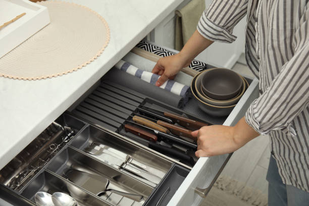 Woman taking towel from open drawer of kitchen cabinet, closeup