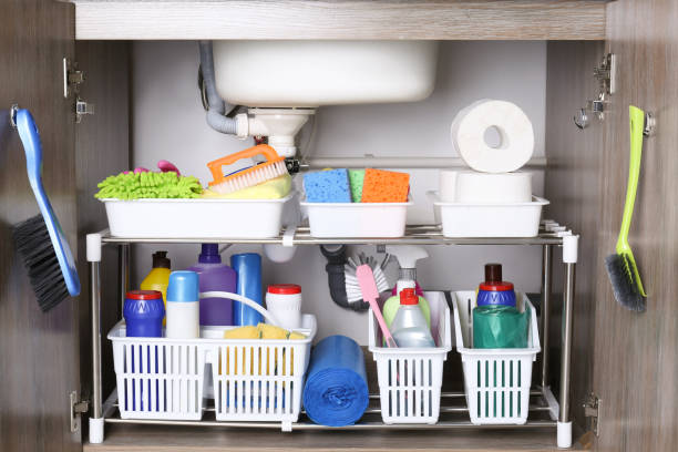 Open under sink cabinet with different cleaning supplies in kitchen